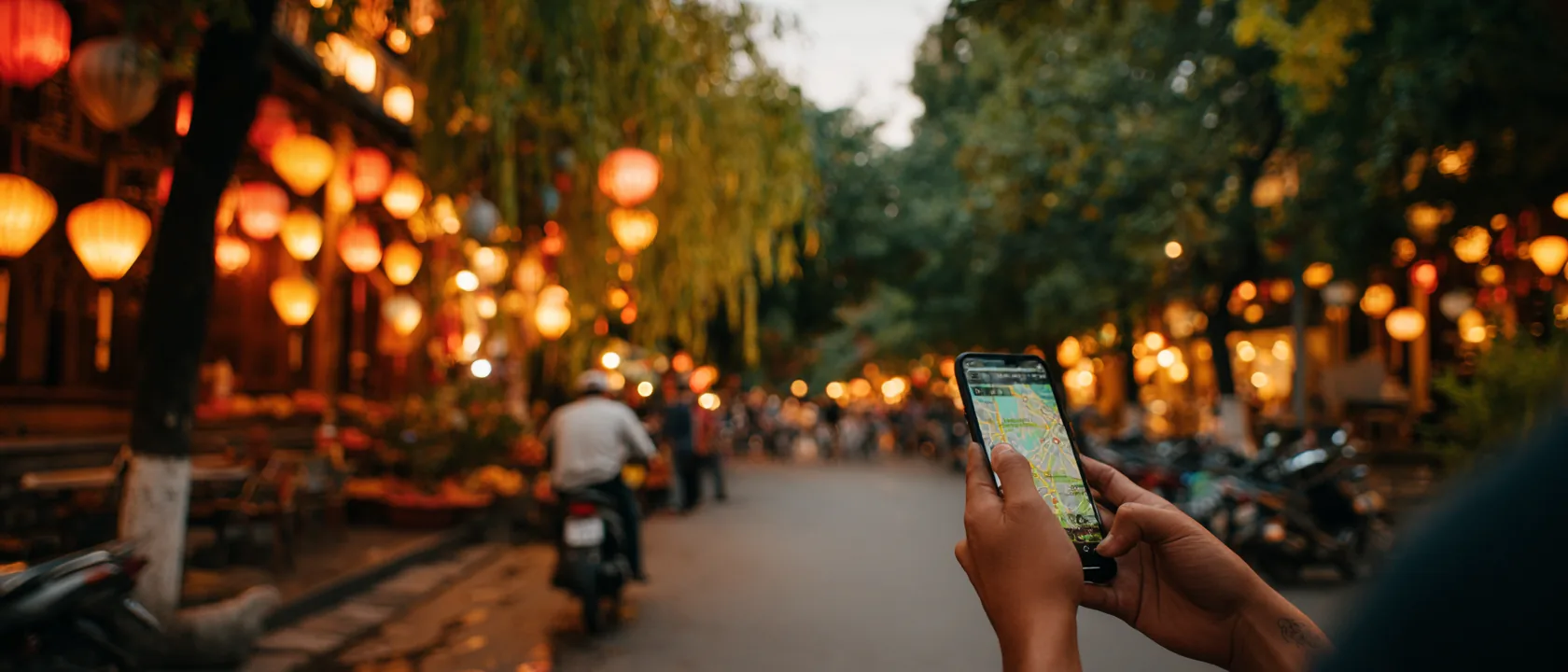 A hand holding a phone with navigation on a lantern-lit Hoi An street