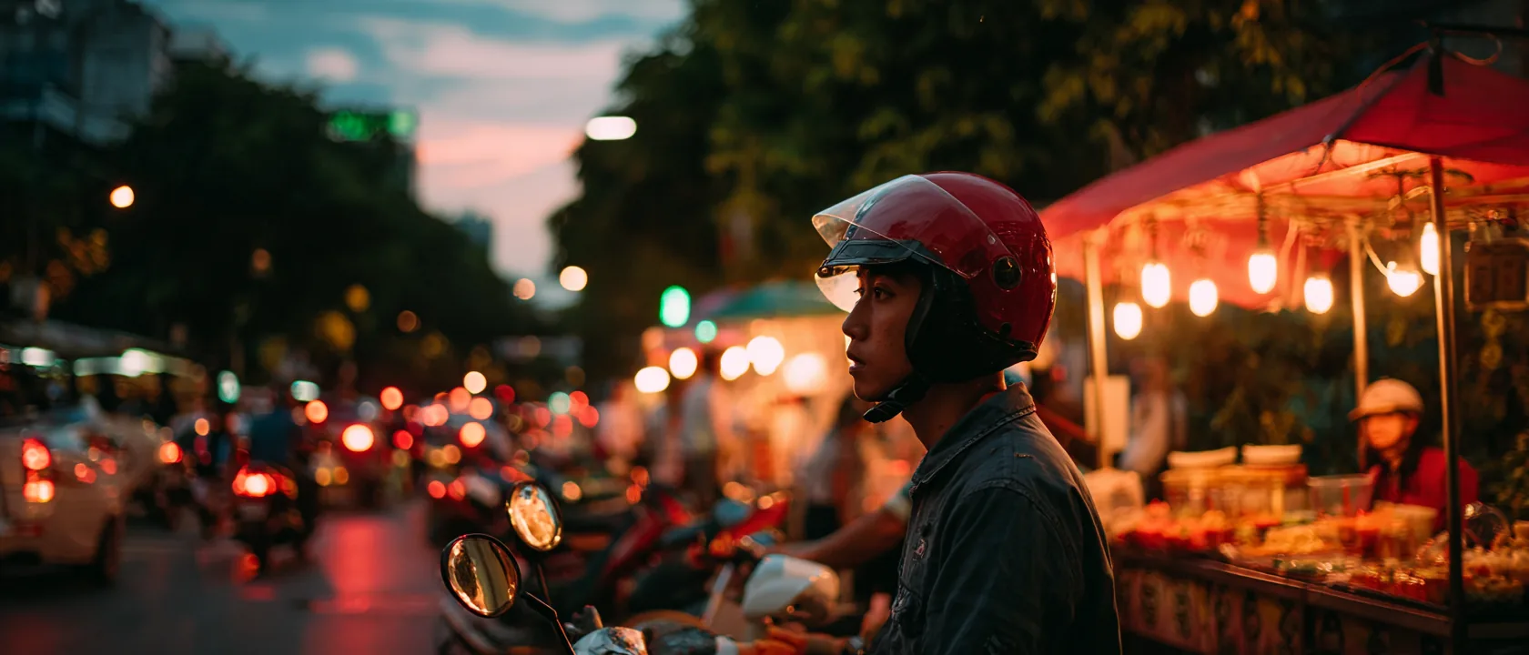 Rider in an open-face helmet on a rental scooter in evening Chiang Mai traffic